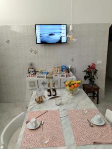 a kitchen with a table with a tv on the wall at A CASA IDA in Bagnoregio
