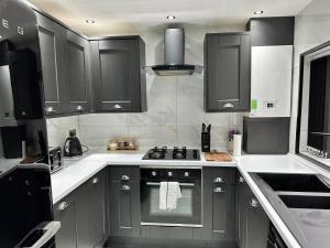 a kitchen with black cabinets and a stove top oven at 4 bed 4 bath House with Free Parking, 5 Mins to LFC and 15 Mins to City Centre in Liverpool