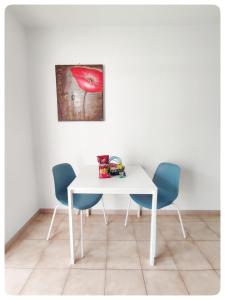 a white dining room table with two chairs and a painting at Castle Margherita's Apartments in Los Cristianos