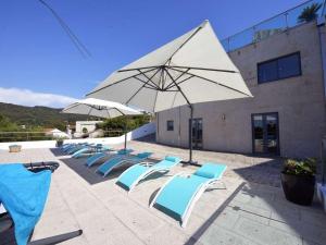 a group of lounge chairs and an umbrella at Charming Caminha Villa - 4 Bedrooms - Villa Caminha View - Private Pool and Astounding Sea Views - Viana do Castelo in Caminha