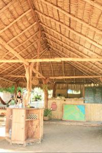Eine Frau, die an einem Tresen unter einem Holzdach steht. in der Unterkunft Camping Ojo de Agua in Nagarote