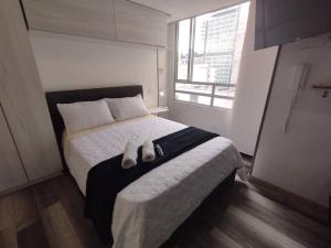 ein Schlafzimmer mit einem Bett mit zwei Hausschuhen darauf in der Unterkunft Centro Histórico Bogotá: Estilo Ejecutivo in Bogotá