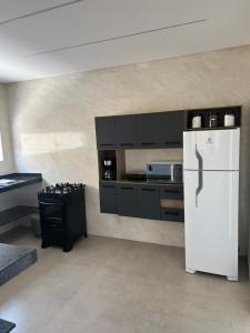uma cozinha com um frigorífico branco e armários pretos em Casa Beija-Flor em Paraty