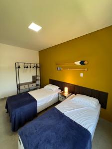 um quarto com 2 camas e uma parede amarela em Casa Beija-Flor em Paraty