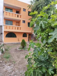 pomarańczowy budynek z ogródkiem przed nim w obiekcie 2 Cuarto independiente en Ambato w mieście Ambato