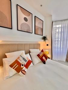 een slaapkamer met een wit bed met kussens erop bij Apartment Malaussena - Reception 24&7 - Center Libération in Nice