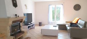 ein Wohnzimmer mit einem Sofa und einem TV in der Unterkunft Escale Côte et Mer in Clohars-Fouesnant