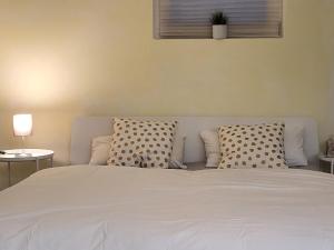 a white bed with two pillows and a window at Yoga Atelier Vaihingen Enz in Vaihingen an der Enz