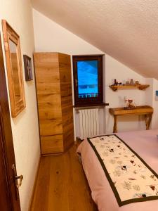 1 dormitorio con cama, ventana y TV en mansardacourmayeur, en Courmayeur