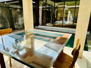 a glass table on a balcony with a swimming pool at Wana Karsa The Villas Ubud in Ubud