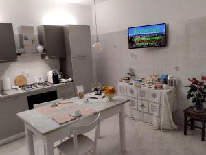 a kitchen with a white table and a tv on the wall at A CASA IDA in Bagnoregio