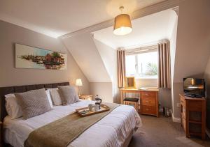 a bedroom with a bed and a desk and a window at Orchard House Wadebridge Self Catering in Wadebridge