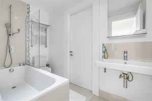 un bagno bianco con vasca e lavandino di Earls Court Spacious Apartment a Londra