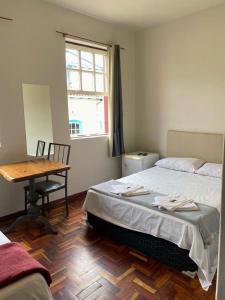 a bedroom with a bed and a table and a window at Casa do Alferes in Ouro Preto