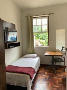 a bedroom with a bed and a desk and a window at Casa do Alferes in Ouro Preto