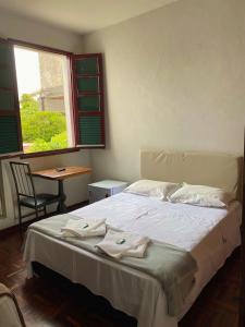a bedroom with a large bed with towels on it at Casa do Alferes in Ouro Preto