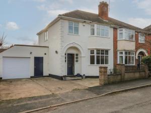 een wit huis met een garage in een straat bij 2 Gladstone Avenue in Melton Mowbray