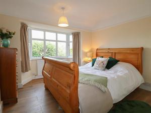 een slaapkamer met een houten bed en een raam bij 2 Gladstone Avenue in Melton Mowbray