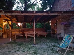 a wooden pergola with wooden tables and a chair at Przystanek Rospuda in Sucha Wieś
