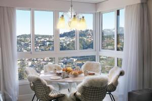 a dining room with a table and chairs and windows at Residencial Via Florida Gramado in Gramado