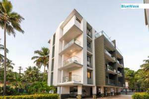 a white building with palm trees in front of it at Luxury 2BHK Apartment Near Candolim in Nerul