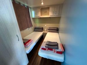 twee bedden in een kleine kamer met witte kasten bij Kamp Slanik Mobile Homes in Umag