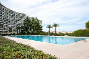 duży basen obok wysokiego budynku w obiekcie Cannes Marina suite vue mer w mieście Mandelieu-la-Napoule