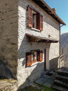 - un bâtiment ancien avec des fenêtres et des escaliers en bois dotés de volets dans l'établissement Chalet Alpe Quaggiui, à Calasca Castiglione