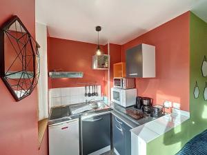a kitchen with red walls and a counter top at Appartement à 30 m de la plage - balcon - proche Centre - WIFI -Le Cérès 3 in Berck-sur-Mer