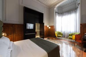 a bedroom with a bed and a tv and chairs at Boutique Hotel Cordial Malteses in Las Palmas de Gran Canaria