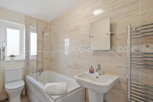 a bathroom with a sink and a tub and a toilet at 4 Bed House with Parking and Garden - Sleeps 8 in Kent