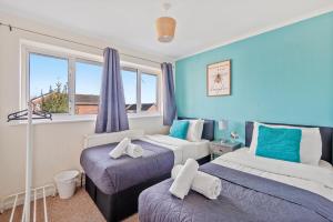 - 2 lits dans une chambre aux murs bleus et aux fenêtres dans l'établissement 4 Bed House with Parking and Garden - Sleeps 8, à Kent