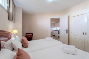 a bedroom with two white beds and a kitchen at OBSIDIAN Apartamento Santa María in Adeje