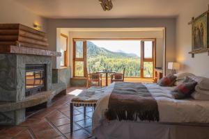 a bedroom with a fireplace and a bed with a view at HOTEL NOMADES PATAGONIA in Coihaique