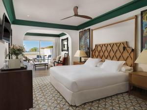 a bedroom with a large white bed and a living room at H10 Estepona Palace in Estepona