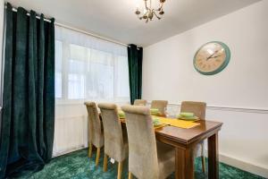 a dining room table with chairs and a clock on the wall at Quaint 3-Bedroom Retreat in Reading with Parking in Tilehurst