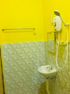 La salle de bains jaune est pourvue d'un lavabo et d'une douche. dans l'établissement The Pines Studio @ PCB (deluxe), à Kota Bharu