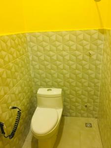 La salle de bains est pourvue de toilettes et d'un mur jaune. dans l'établissement The Pines Studio @ PCB (deluxe), à Kota Bharu