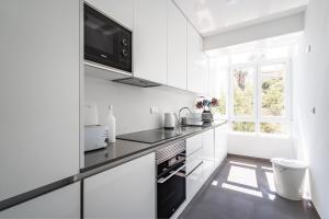 a white kitchen with black appliances and a window at Akicity Benfica Zenith in Lisbon