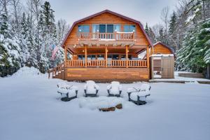 a log cabin in the snow with snow covered chairs at Pittsburg Lake House with Magalloway Mountain Views! in Pittsburg