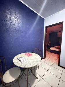 ポソス・デ・カルダスにあるFree Way Motelの青い壁の客室で、テーブルと椅子が備わります。