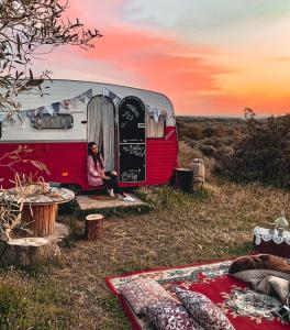 a woman sitting outside of a red and white van at SA MOLA GLAMPING EXPERIENCE Roulotte in Escolca