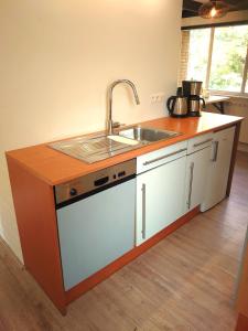 een keuken met een wastafel en een aanrecht met een wastafel bij Vrijstaande vakantiebungalow met optimale privacy!! in Rekem