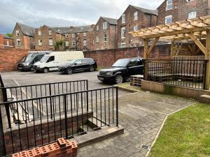 a parking lot with cars parked in front of a brick building at Lovely 3 Dbl Bed (sleeps upto 6) close to centre. in Manchester