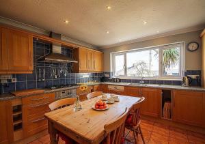 a kitchen with a wooden table and a large window at Orchard House Wadebridge Self Catering in Wadebridge