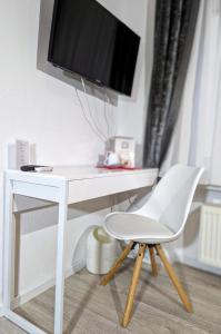 a white desk with a tv and a white chair at City Hotel - Einzelzimmer in Rastatt