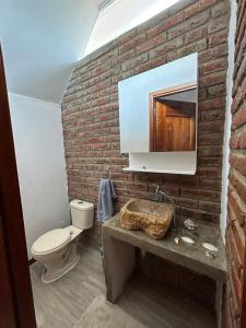 a brick walled bathroom with a toilet and a sink at Casa Caballito de mar-Seahorse House in Bahía de Caráquez
