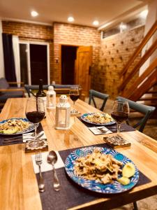 Casa Caballito de mar-Seahorse House في باهيا دو كاراكويز: طاولة خشبية مع لوحات من الطعام وكؤوس النبيذ