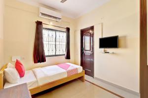 a bedroom with a bed and a tv on the wall at OYO Flagship Sunder Nivas in Bangalore