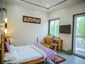 a bedroom with a bed and a desk and a television at The Arham Resort in Udaipur